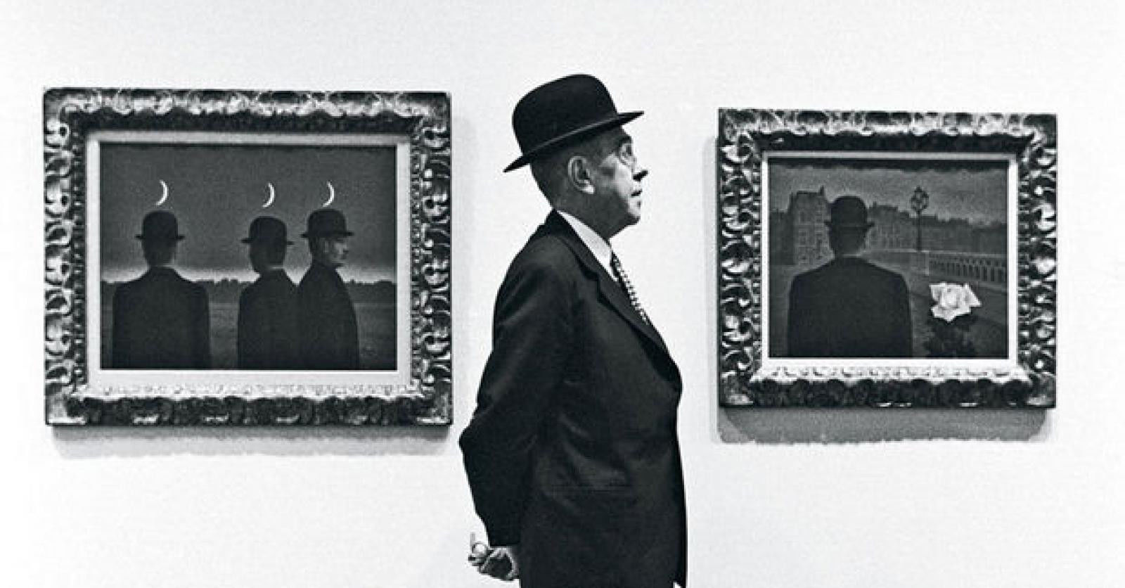 René Magritte, posing in front of his magical realistic paintings  